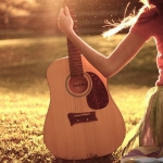 Аватар Девушка сидит на траве и держит в руках гитару