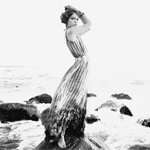 Аватар Девушка в развеваящемся платье стоит на морских камнях